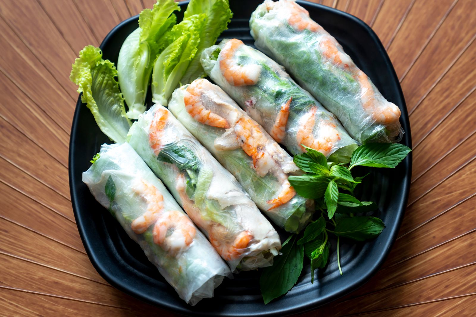Fresh rice paper rolls with prawn and herbs on a dark plate